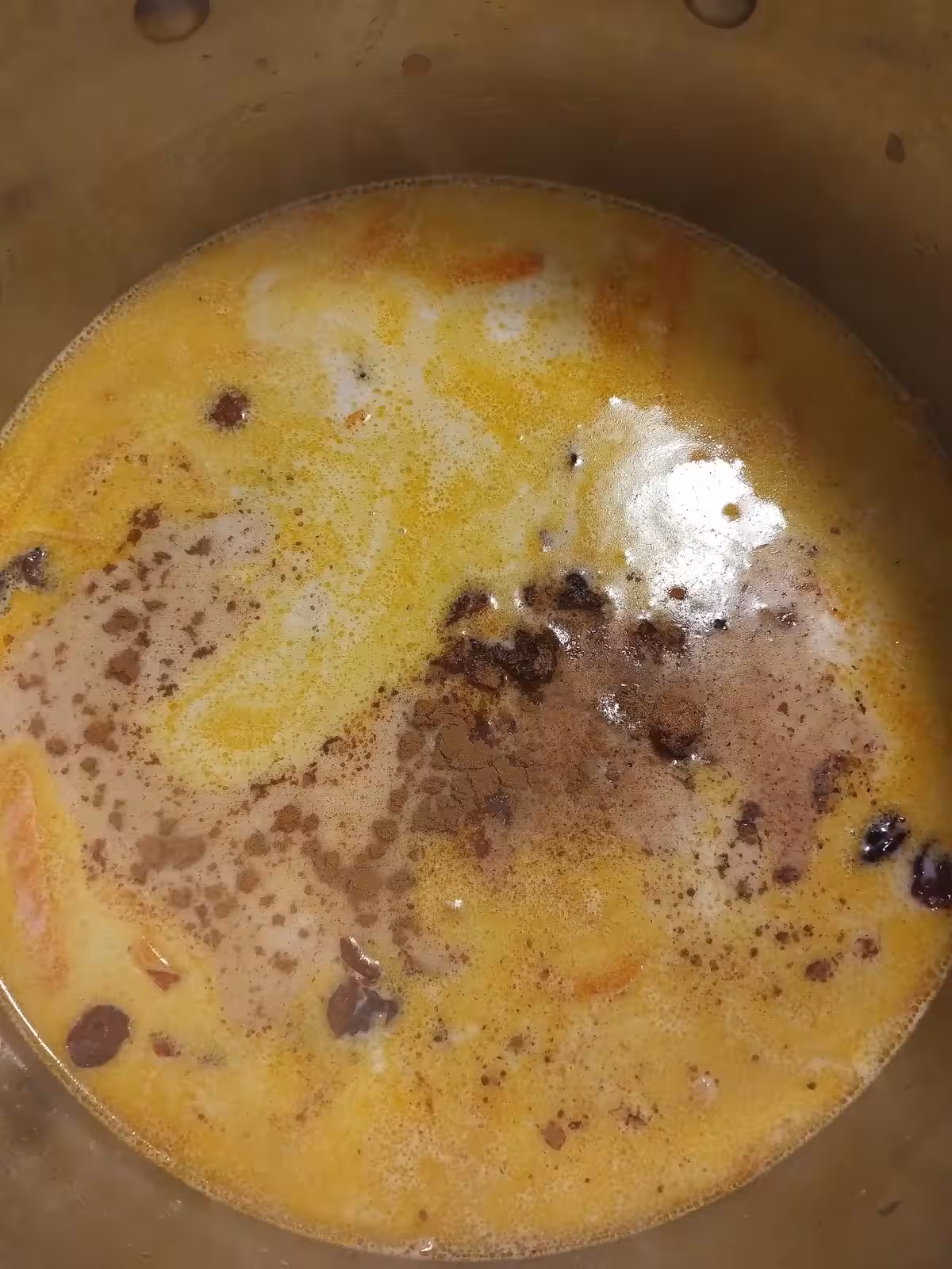 Mélange des lentilles corail, des carottes, du lait végétal, des raisins et des épices